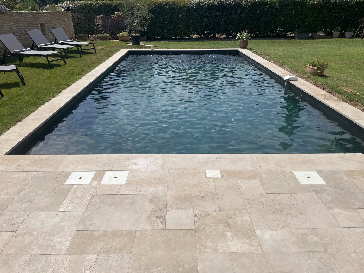 Photo Airbnb avant : piscine austère, transats vides, lumière de midi