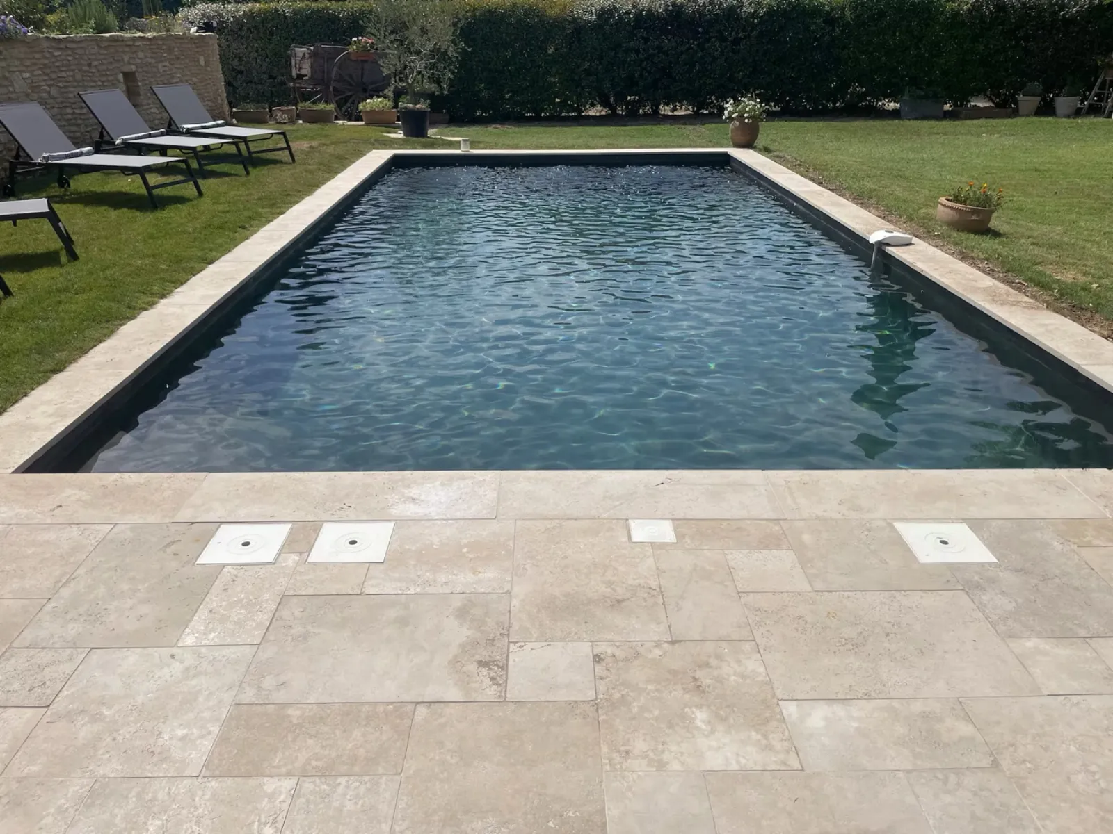 Photo Airbnb avant : piscine austère, transats vides, lumière de midi