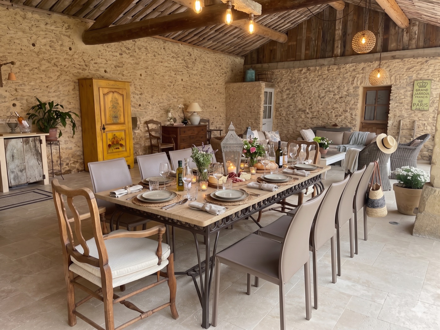 Cuisine d'été en pierre après retouche IA, table dressée pour douze personnes avec lanterne, fleurs, pain, huile d'olive