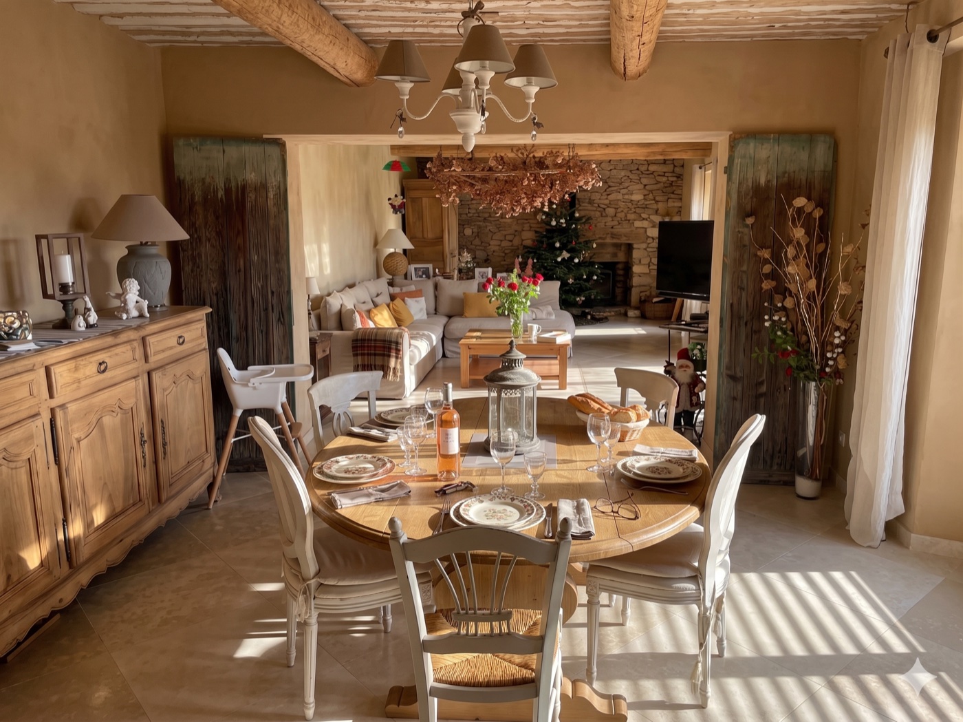 Même salle après retouche, table dressée avec couverts, verres, bouteille de rosé, fleurs, pain